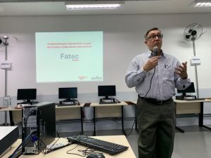 palestrante falando ao microfone e projeção de slides na parede ao fundo